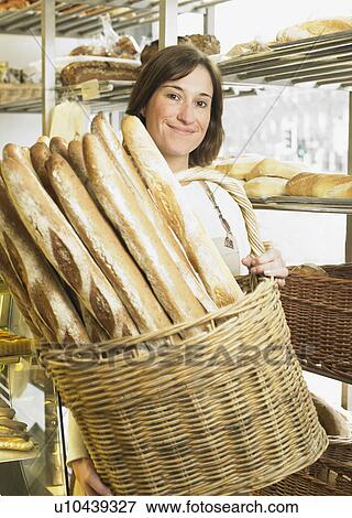 Female baker holding basket of baguettes, smiling, portrait View Large Photo Image Stock Photo - Female baker holding basket of baguettes, smiling, portrait. Fotosearch