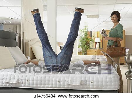 Man falling back onto bed in a store. View Large Photo Image Picture - Man falling back onto bed in a store.. Fotosearch