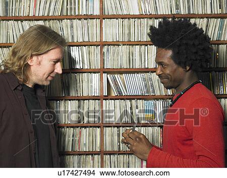 Man showing mature man compact disc in music shop, smiling View Large Photo Image Picture - Man showing mature man compact disc in music shop, smiling. Fotosearch