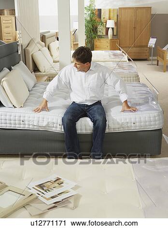 Man sitting on bed in furniture store. View Large Photo Image Stock Image - Man sitting on bed in furniture store.. Fotosearch