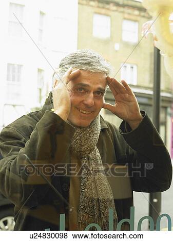 Mature man peering into shop window, smiling View Large Photo Image Stock Photo - Mature man peering into shop window, smiling. Fotosearch