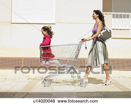Mother pushing daughter (5-7) in supermarket trolley, Alicante, Spain, View Large Photo Image Stock Photo - Mother pushing daughter (5-7) in supermarket trolley, Alicante, Spain,. Fotosearch