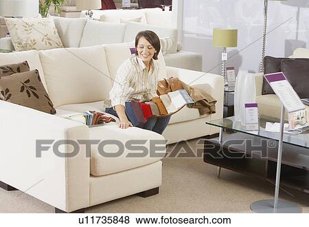 Woman sitting on sofa in furniture store. View Large Photo Image Stock Photo - Woman sitting on sofa in furniture store.. Fotosearch
