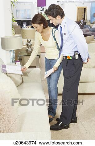 Picture - Woman talking to salesman in sofa shop.. Fotosearch