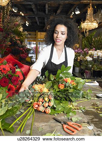 Young female florist preparing bouquet in shop, smiling View Large Photo Image Stock Photo - Young female florist preparing bouquet in shop, smiling. Fotosearch