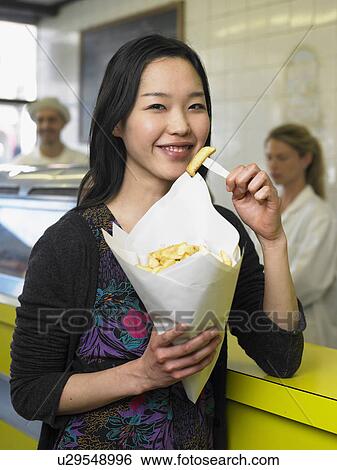 Young woman eating chips in fish and chip shop smiling, portrait View Large Photo Image Stock Photograph - Young woman eating chips in fish and chip shop smiling, portrait. Fotosearch