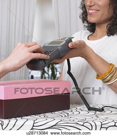 Young woman holding credit card reader for customer, close-up View Large Photo Image Picture - Young woman holding credit card reader for customer, close-up. Fotosearch