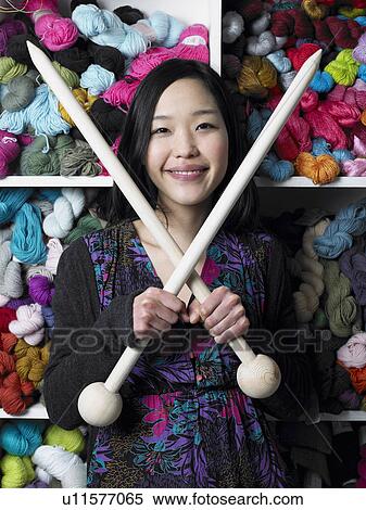 Young woman holding giant knitting needles, smiling, portrait View Large Photo Image Stock Photography - Young woman holding giant knitting needles, smiling, portrait. Fotosearch