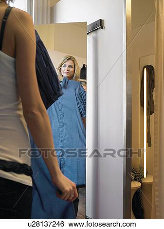 Young woman looking at dress in mirror View Large Photo Image Stock Photograph - Young woman looking at dress in mirror. Fotosearch