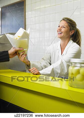 Young woman serving customer in fish and chip shop, smiling View Large Photo Image Stock Photograph - Young woman serving customer in fish and chip shop, smiling. Fotosearch