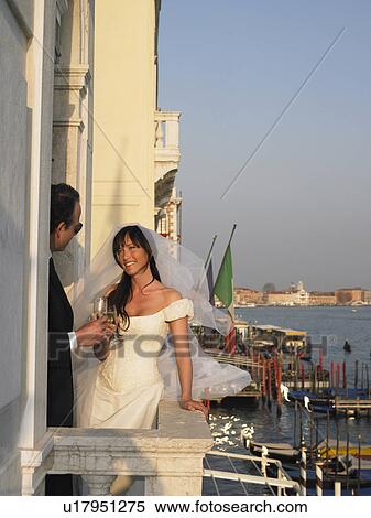 Stock Photography - Bride and groom on balcony having a toast. Venice, Italy.. Fotosearch