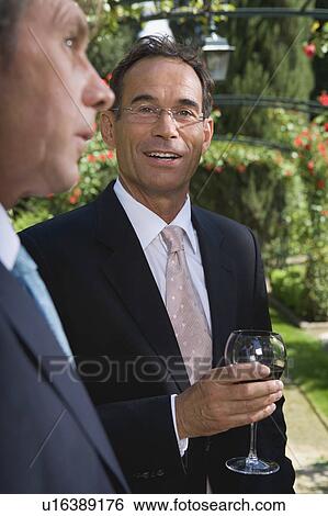 Stock Photograph - Businessmen drinking wine in a garden. Fotosearch