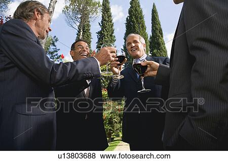 Four businessmen drinking wine in a garden View Large Photo Image Stock Photo - Four businessmen drinking wine in a garden. Fotosearch