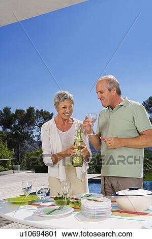 Stock Image - Man and woman drinking by poolside.. Fotosearch