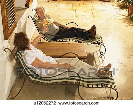 Senior couple lying on sun loungers toasting each other with champagne View Large Photo Image Stock Image - Senior couple lying on sun loungers toasting each other with champagne. Fotosearch
