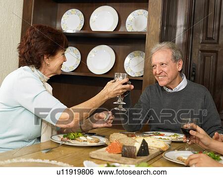 Senior couple toasting each other with wine at family lunch View Large Photo Image Stock Photograph - Senior couple toasting each other with wine at family lunch. Fotosearch