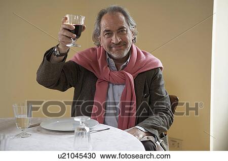 Senior man holding up wine at table, portrait View Large Photo Image Stock Image - Senior man holding up wine at table, portrait. Fotosearch
