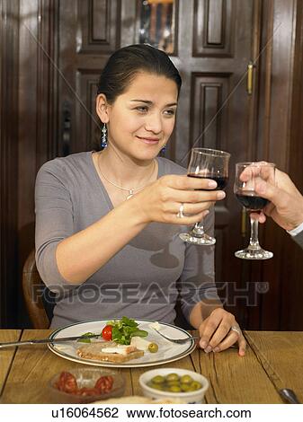 Young woman toasting glass of red wine at lunch, smiling View Large Photo Image Stock Image - Young woman toasting glass of red wine at lunch, smiling. Fotosearch