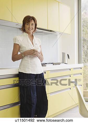 Senior woman standing in kitchen View Large Photo Image Stock Image - Senior woman standing in kitchen. Fotosearch