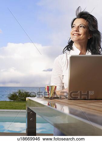 Woman on laptop out doors on decking View Large Photo Image Stock Photograph - Woman on laptop out doors on decking. Fotosearch