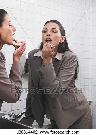 Woman reflected in office washroom mirror applying make-up View Large Photo Image Stock Image - Woman reflected in office washroom mirror applying make-up. Fotosearch