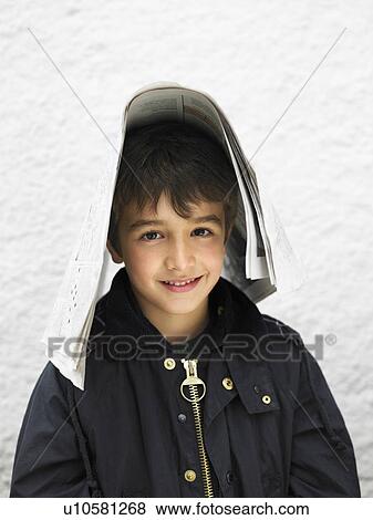 Stock Photo - Boy (6-8) outdoors, covering head with newspaper. Fotosearch
