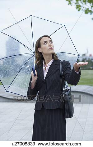 Businesswoman armed with umbrella checking whether it stopped raining. View Large Photo Image Stock Photo - Businesswoman armed with umbrella checking whether it stopped raining.. Fotosearch