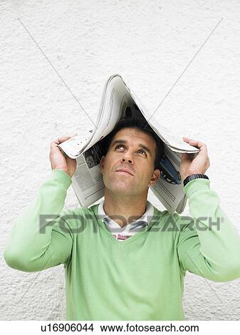 Man covering head with newspaper, looking up View Large Photo Image Picture - Man covering head with newspaper, looking up. Fotosearch