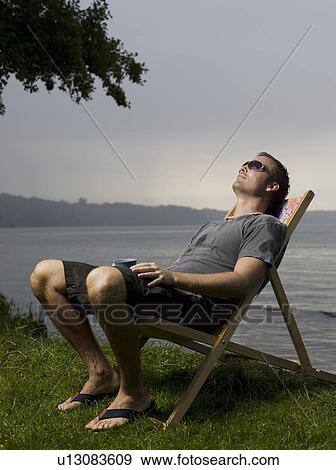 Man sitting in garden chair outdoors View Large Photo Image Stock Photo - Man sitting in garden chair outdoors. Fotosearch
