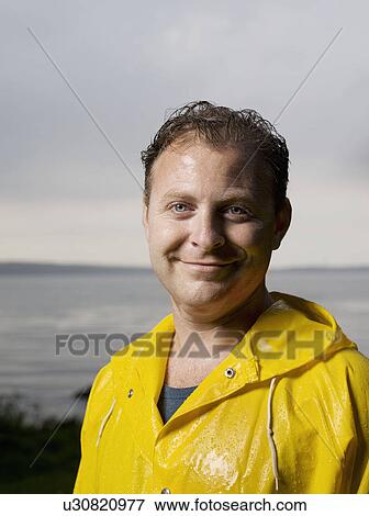 Man standing in raincoat smiling View Large Photo Image Stock Photo - Man standing in raincoat smiling. Fotosearch