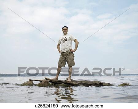 Man standing on rocks in water View Large Photo Image Stock Image - Man standing on rocks in water. Fotosearch