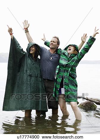 Stock Image - Two women and man standing in water. Fotosearch