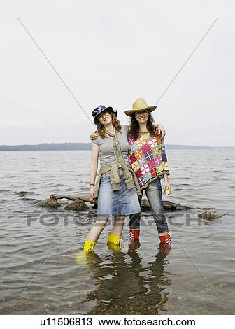 Stock Image - Two women standing in shallow water. Fotosearch