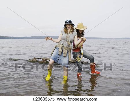 Stock Photography - Two women standing in shallow water. Fotosearch