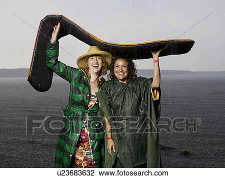 Two women taking shelter from the rain View Large Photo Image Stock Image - Two women taking shelter from the rain. Fotosearch