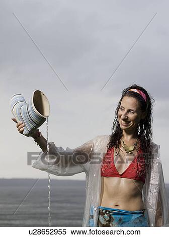 Stock Photography - Woman pouring water out off rubber boot. Fotosearch