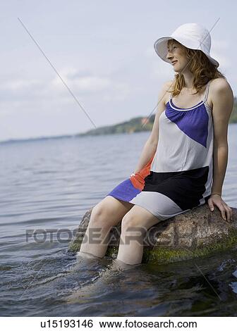 Woman sitting on rock in water View Large Photo Image Stock Photograph - Woman sitting on rock in water. Fotosearch