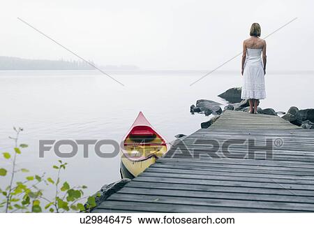 Stock Photography - Woman standing on a dock near a boat.. Fotosearch