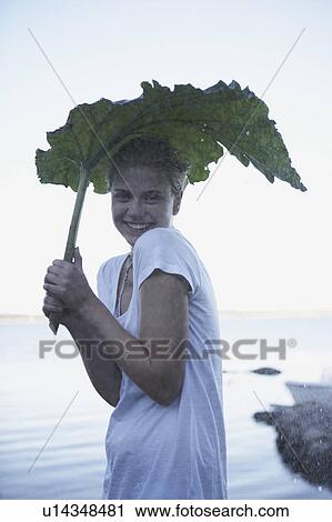 Stock Image - Young Woman sheltering from rain.. Fotosearch