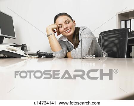 Businesswomen sitting at her desk with a Newton's Cradle View Large Photo Image Stock Image - Businesswomen sitting at her desk with a Newton's Cradle. Fotosearch