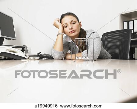 Businesswomen sitting at her desk with a Newton's Cradle View Large Photo Image Stock Photograph - Businesswomen sitting at her desk with a Newton's Cradle. Fotosearch