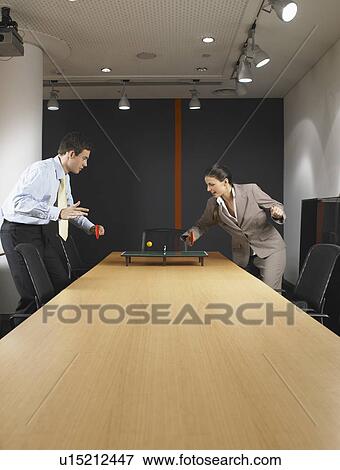 Man and woman playing miniature ping pong at boardroom table View Large Photo Image Stock Photo - Man and woman playing miniature ping pong at boardroom table. Fotosearch