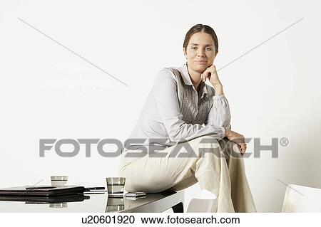 Young business woman seated on desk. View Large Photo Image Stock Image - Young business woman seated on desk.. Fotosearch