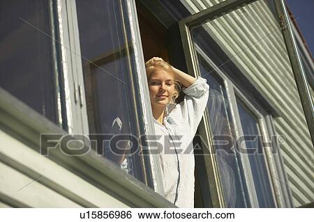 Stock Photograph - Young woman appearing from window.. Fotosearch