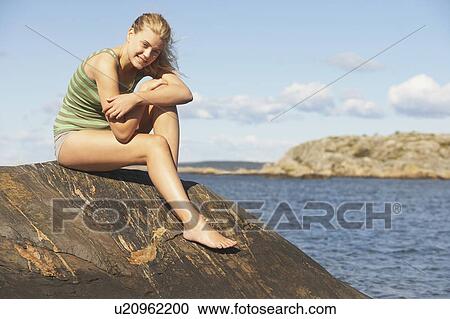 Stock Image - Young Woman doing Yoga on rocks.. Fotosearch