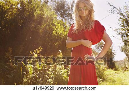 Stock Photo - Young woman in nature wearing red dress. Fotosearch