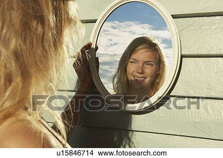 Young Woman Looking in Mirror outside. View Large Photo Image Picture - Young Woman Looking in Mirror outside.. Fotosearch