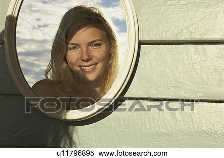 Stock Photography - Young Woman Looking in Mirror outside.. Fotosearch