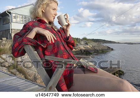Stock Photo - Young Woman relaxing on jetty.. Fotosearch