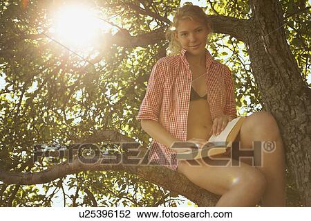 Young Woman sitting in tree. View Large Photo Image Stock Image - Young Woman sitting in tree.. Fotosearch